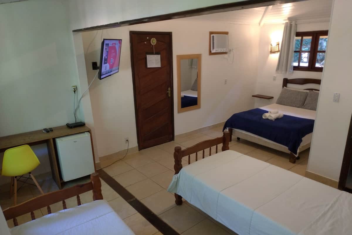 Ein Schlafzimmer mit einem Bett, einem Schreibtisch mit Stuhl, einem kleinen Kühlschrank und einem Spiegel an der Wand.