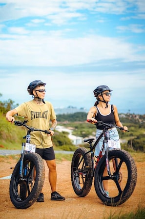 Twee personen op een onverhard pad met fietsen, ze dragen helmen en casual kleding.