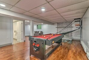 A pool table in a room with wooden flooring, a brick wall, and a staircase.