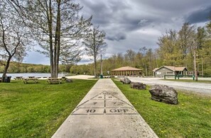 A shuffleboard court with a picnic area, a small building, and a lake in the background.