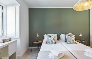 Et hotelværelse med en seng, to sengeborde, et skrivebord og et vindue.