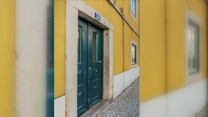 Ein gelbes Gebäude mit einer grünen Tür und einem kleinen Fenster.