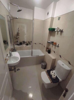 A bathroom with a bathtub, sink, toilet, and a glass-enclosed shower.