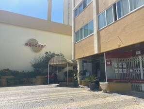 Un edificio con un letrero que dice 'Ecuador' y un área de estar al aire libre cubierta con plantas en macetas.