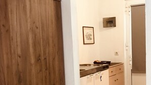 A kitchen with wooden cabinets, a countertop, and a door leading to another room. - Pension Zoi (Rhodes)