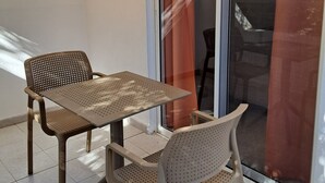A small outdoor seating area with a table and two chairs, a sliding glass door, and a whiteboard on the wall. - Pension Zoi (Rhodes)