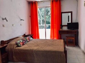 A bedroom with a bed, a desk, a chair, a television, and a window with curtains. - Pension Zoi (Rhodes)