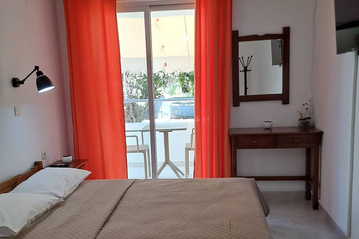 A hotel room with a bed, a desk, a chair, a lamp, and a window with curtains.