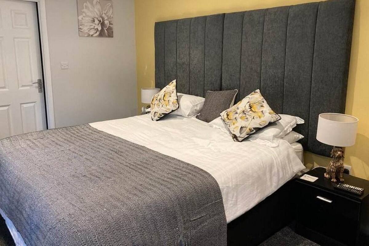 Une chambre d’hôtel avec un lit, une table de chevet, une lampe et une porte.