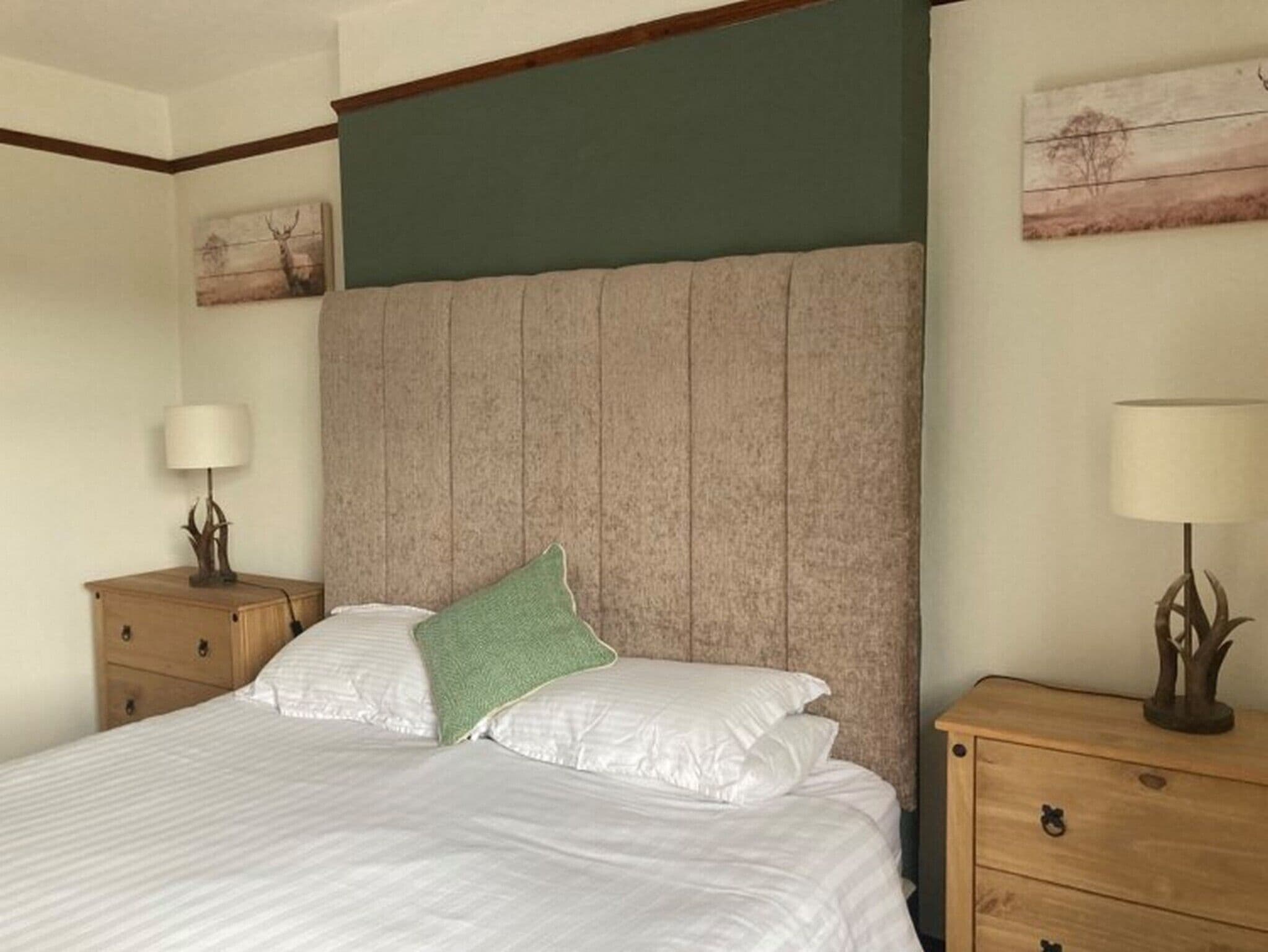 A bedroom with a large bed, two nightstands, and a green accent pillow.