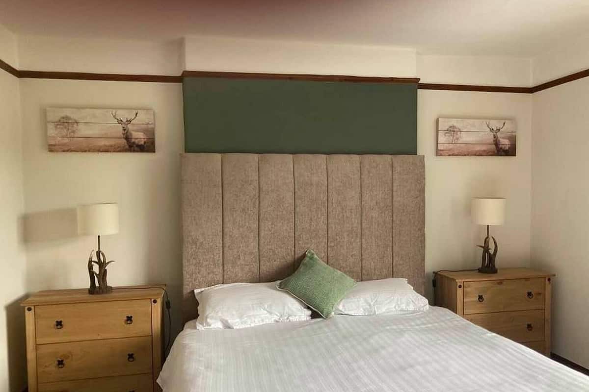 Une chambre d’hôtel avec un grand lit, deux tables de chevet et deux lampes fixées au mur.