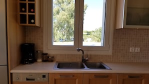 Una cocina con un lavamanos doble, cafetera y lavavajillas.