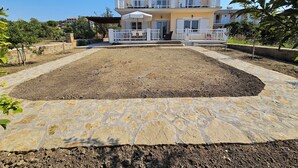 Una casa de dos pisos con un patio empedrado y un camino de piedra que lleva a la entrada.