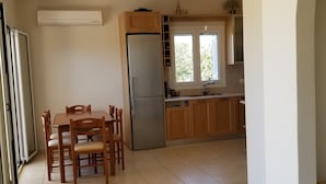 Una cocina amplia con comedor, refrigerador y ventana que proporciona luz natural.