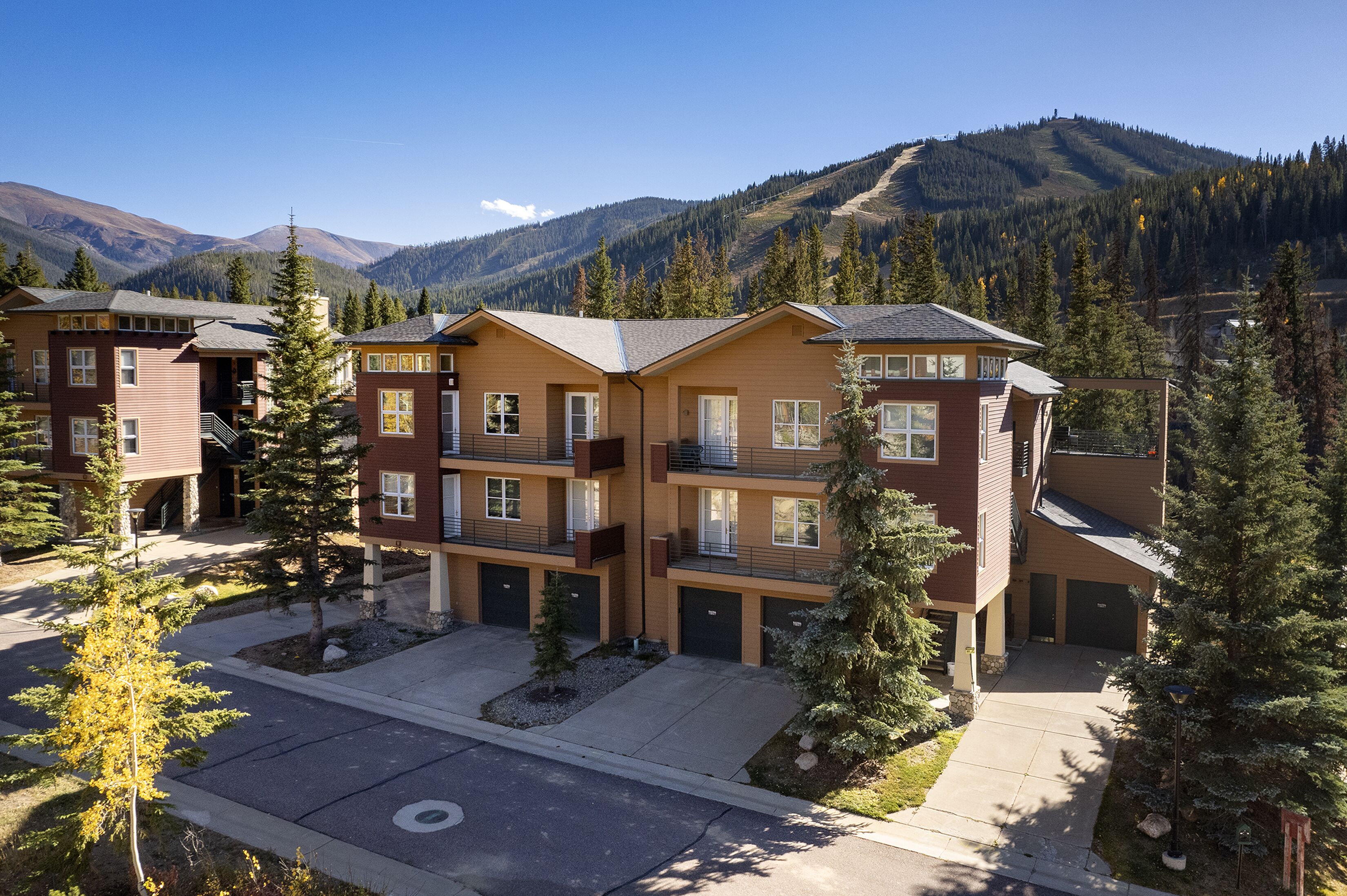 Un hôtel à plusieurs étages doté d’une cour intérieure, entouré d’arbres et avec des montagnes en toile de fond.