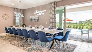 Un comedor con una mesa dispuesta para seis personas, sillas azules y una alfombra estampada.