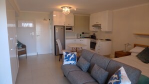 A compact living space with a kitchenette, a sofa, a dining table, and a bed. - Neat Modern Studio in Safe Complex in the Heart of Claremont (Cape Town)