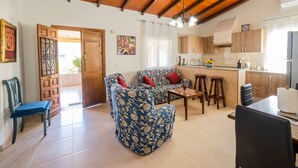 A spacious living room with a sofa and chairs, a dining area with a table, and a kitchen with wooden cabinets and a tiled backsplash. - Cubo's Finca Fernando / private pool / free wifi (Coín)
