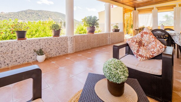 A covered patio with a view of green hills, potted plants, wicker furniture, and a table with chairs. - Cubo's Finca Fernando / private pool / free wifi (Coín)