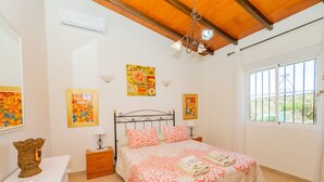 A bedroom with a bed, bedside tables, a dresser, and a window with a view of greenery. - Cubo's Finca Fernando / private pool / free wifi (Coín)