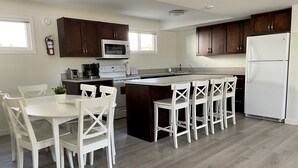 Une cuisine moderne avec un îlot central, des tabourets de bar blancs et un réfrigérateur blanc.