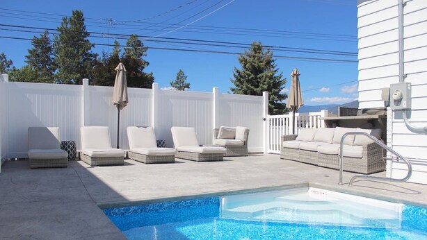 Un jardin avec une piscine, des chaises longues et un espace salon abrité.