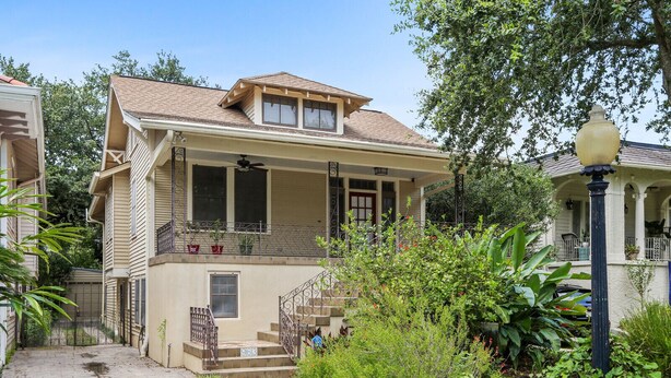 A two-story house with a balcony, a front porch, and a small garden area.