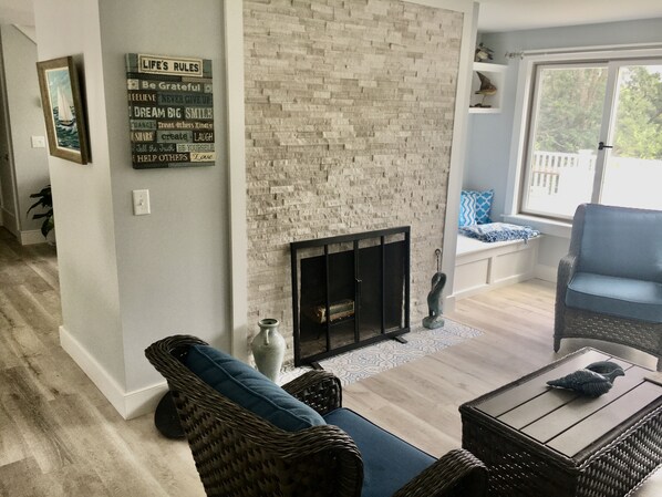 A living room with a brick fireplace, wicker furniture, and a blue couch.