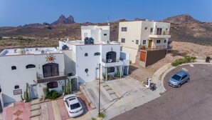 A residential area with modern buildings, a parking area, and a mountainous backdrop. - Casa 12-1 - Pet Friendly, Amazing view, and Newly Renovated (San Carlos)