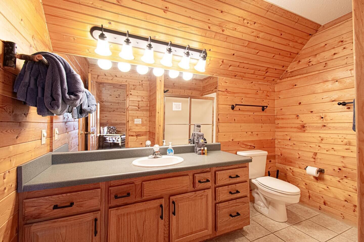 Ein Badezimmer einer Holzhütte mit Waschtisch, Spüle und Toilette.