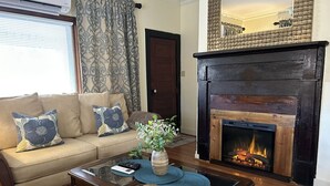 Ein Wohnzimmer mit einem beigefarbenen Sofa, einem Kamin und einer Vase mit Blumen.