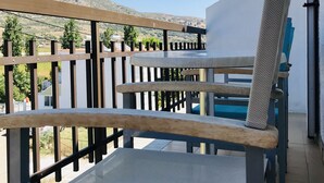 A balcony with a table and chairs, overlooking a mountainous landscape.