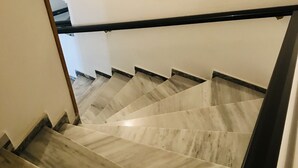 A staircase with a black handrail and beige marble steps.