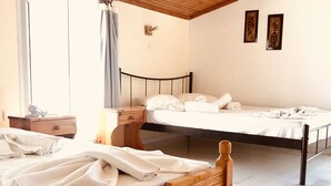 A bedroom with two wooden beds, a wooden ceiling, and a tiled floor.