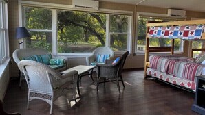 A cozy room with wicker furniture, large windows, and a ceiling fan. - Country Home on 33 acres,  sleeps 18, On the San Saba River! (Voca)