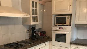 Una cocina con armarios blancos, un microondas, un horno y una estufa a gas.