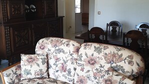 Una sala de estar con un sofá floral, un mueble de madera y una araña.