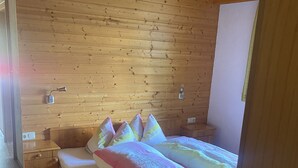Una cama de madera con ropa de cama colorida en una habitación con paredes de madera y techo inclinado.