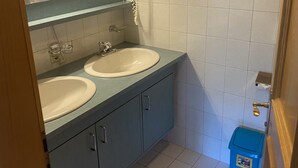 Un baño con dos lavamanos, un espejo y un inodoro.