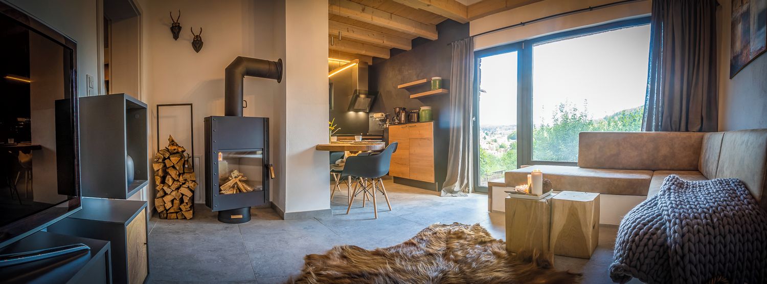 A modern living room with a fireplace, a sofa, a dining area, and a large window with a view.