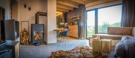 A modern living room with a fireplace, a sofa, a dining area, and a large window with a view.