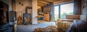 A modern living room with a fireplace, a sofa, a dining area, and a large window with a view.