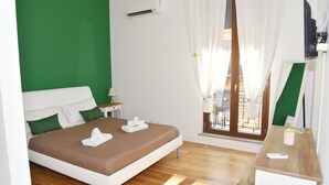 Una habitación de hotel con cama, escritorio, ventana con cortinas y aire acondicionado.