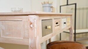 Una mesa de madera con un bol de cristal, un recipiente metálico y un taburete de cuero marrón.