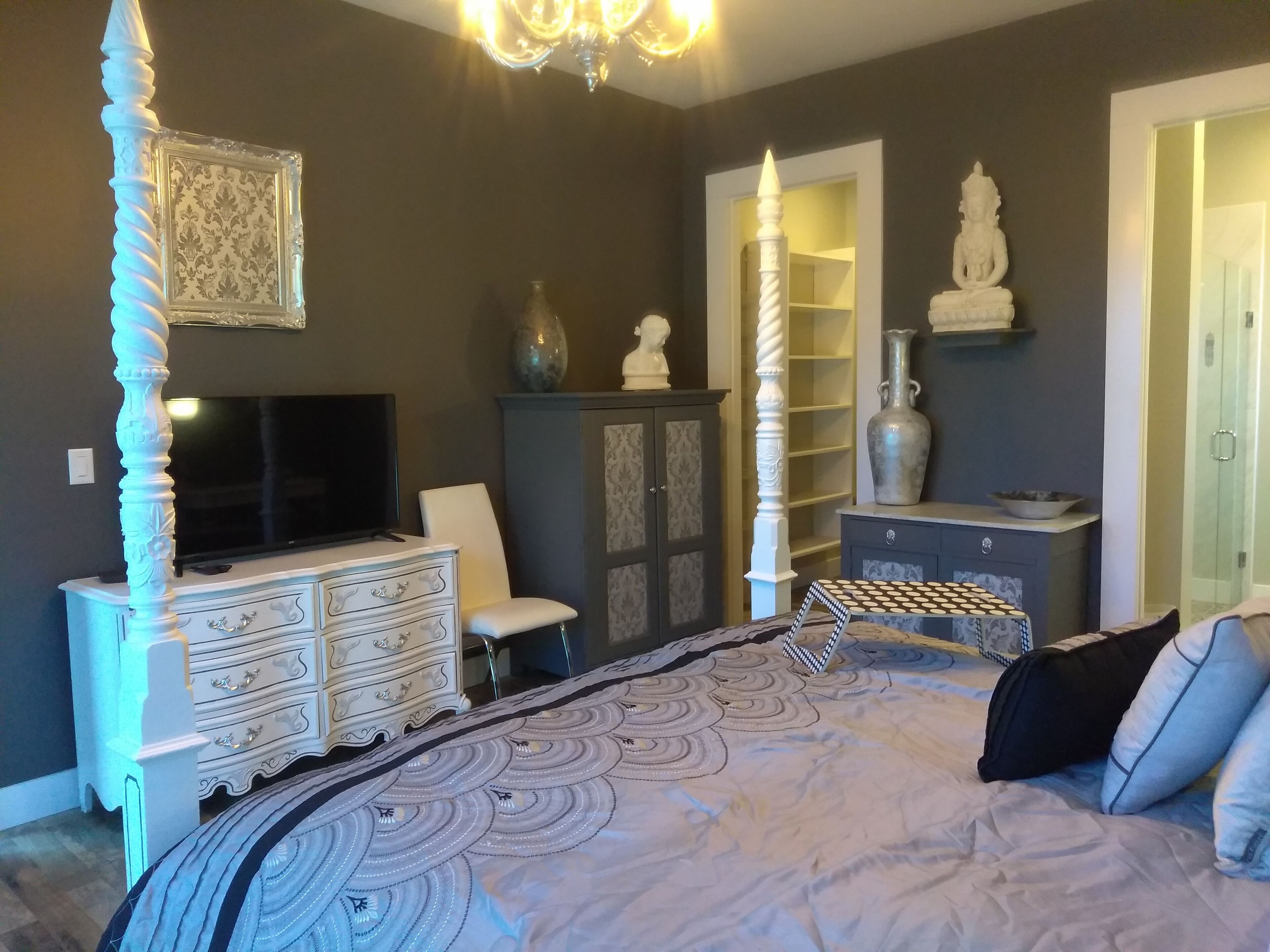 A bedroom with a large bed, a TV, a dresser, and decorative items.