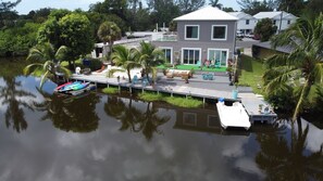 Enjoy waterfront views from the large windows of this two-story house, which features a dock and outdoor seating areas perfect for relaxation and socializing.