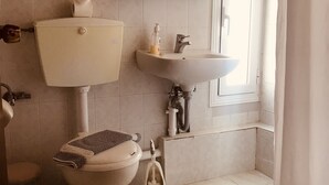 Een badkamer met toilet, wastafel en douche.