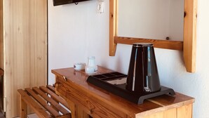 Een houten bureau met een zwarte koffiezetapparaat, een televisie aan de muur en een houten bank.