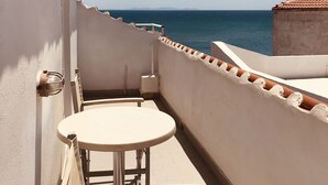 Een balkon met een tafel en stoel, met uitzicht op een heldere blauwe zee.