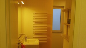 Une petite salle de bain avec un lavabo, une fenêtre et un plancher en bois.
